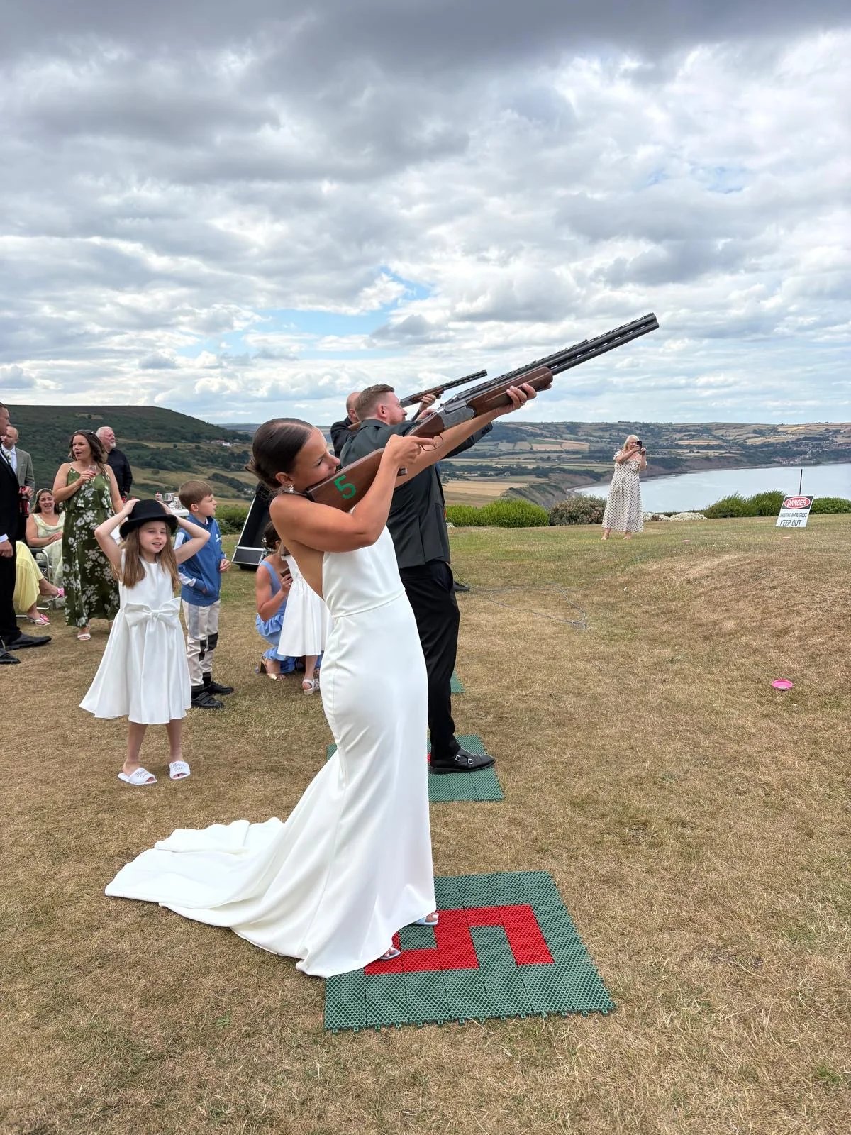Bride Laser Clay Shooting with the coastline behind her