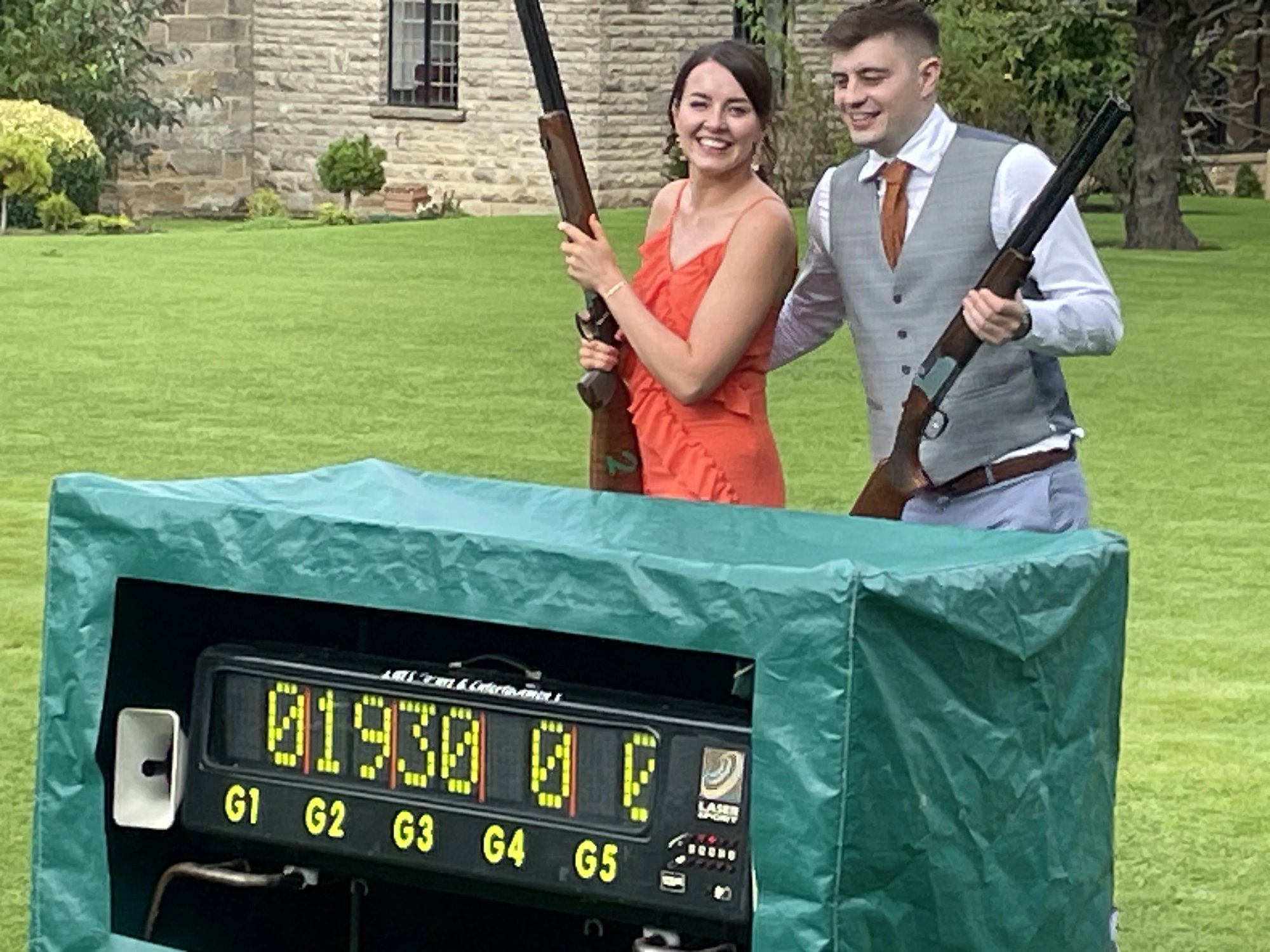 Couple with shotguns beside the laser clay scoreboard